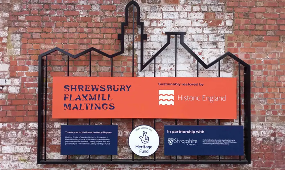 Our acknowledgement stamp amongst other signage and sponsor logos, on a steel frame in the shape of a building fixed to a brick wall