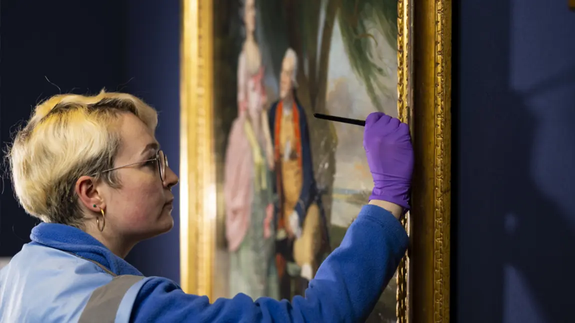 A close up of a person conserving a painting on display in the National Portrait Gallery