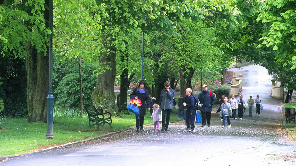 Adults and children walk in Tollcross Park