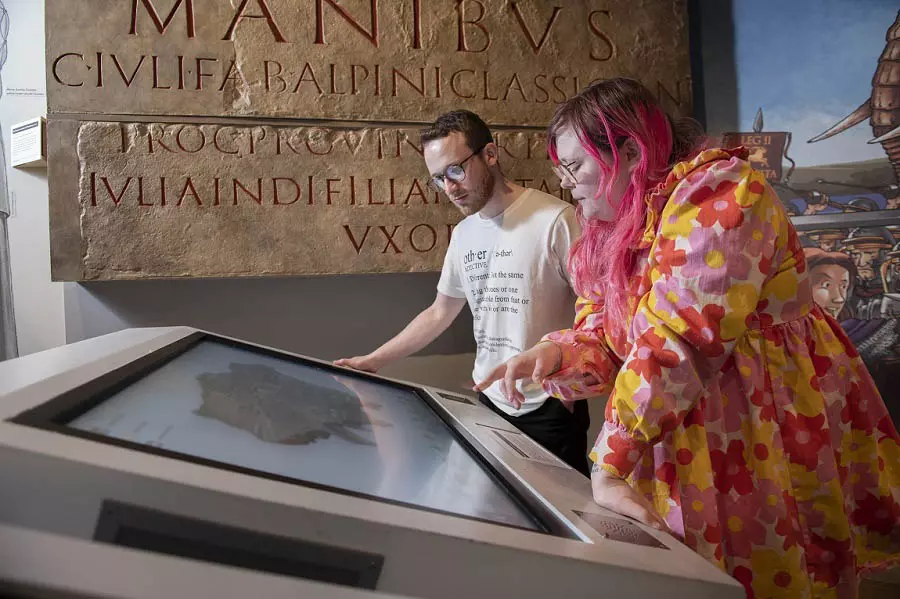 Two people leaning over and reading an interactive screen at a museum