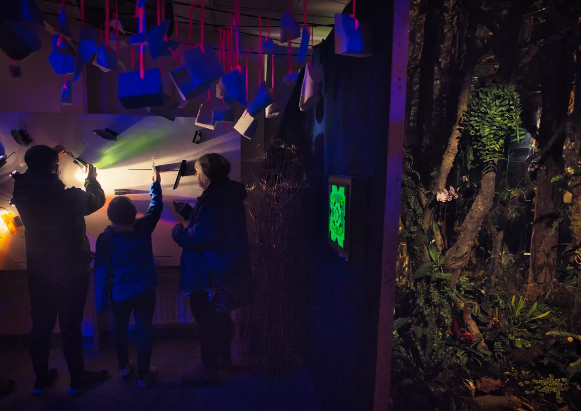 Two adults and a child interact with one of the exhibits